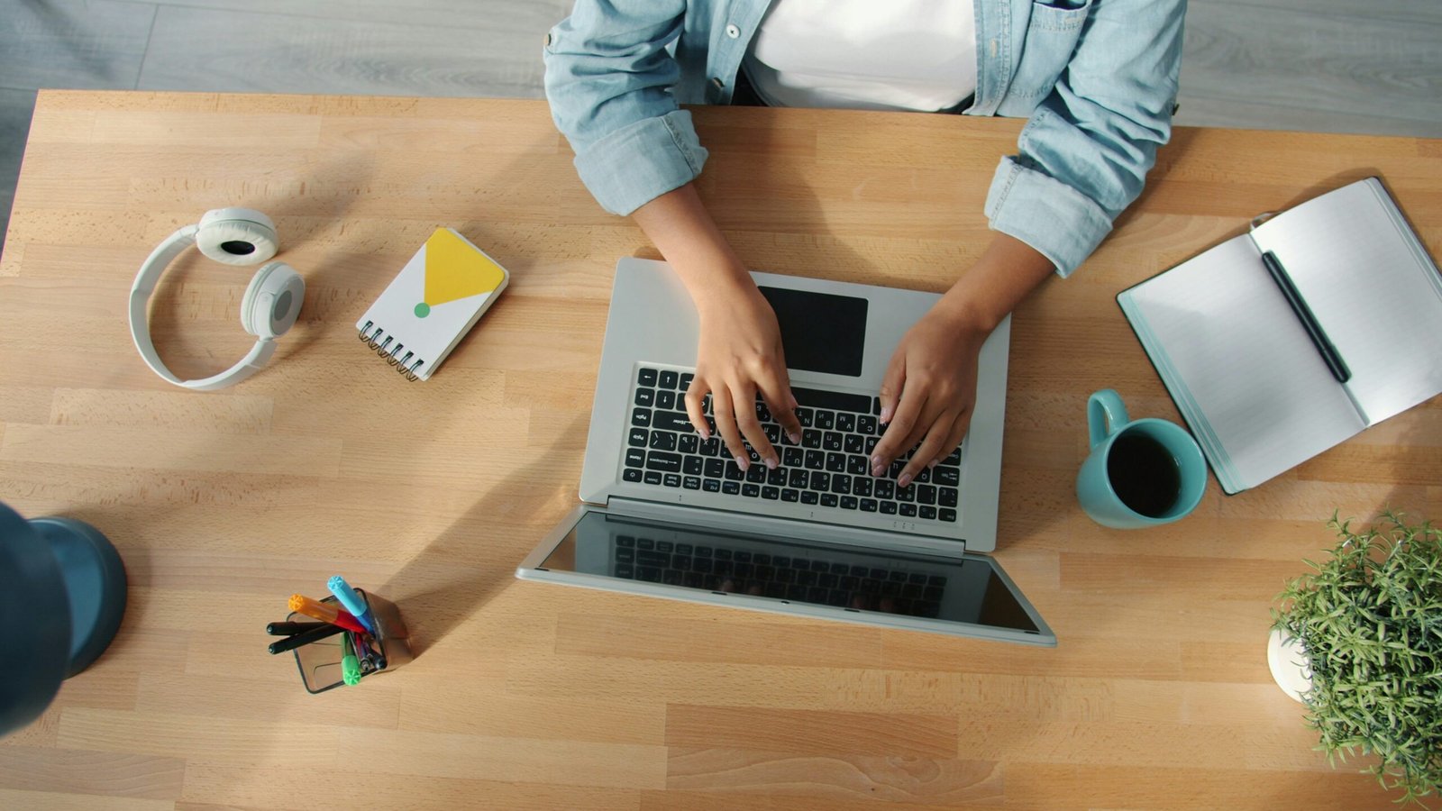Person typing on a laptop at a wooden desk.