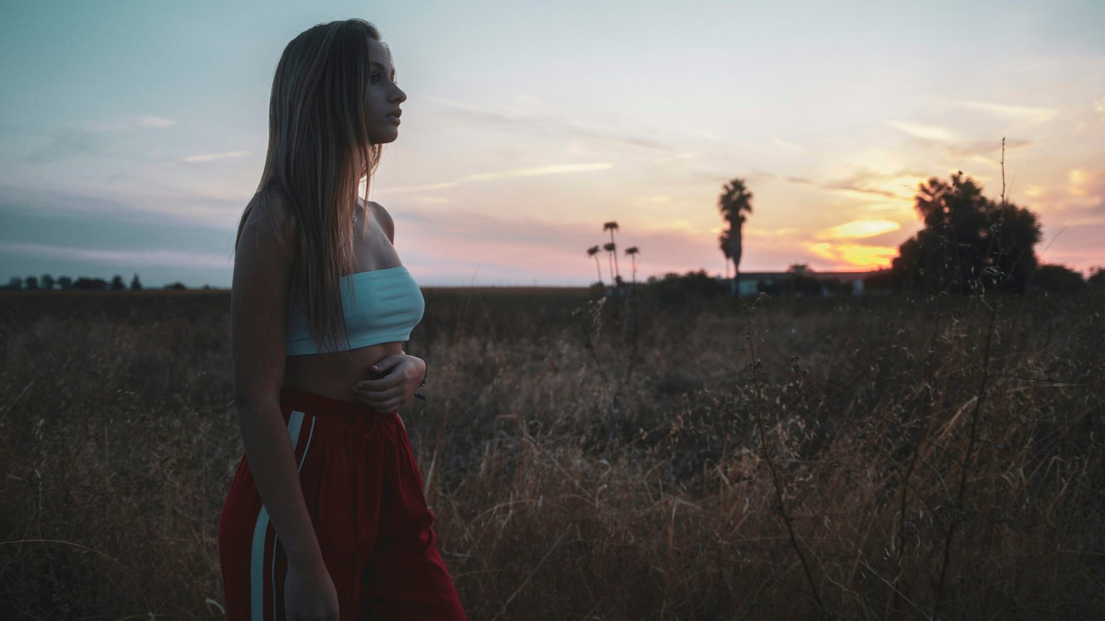 a woman standing in a field at sunset