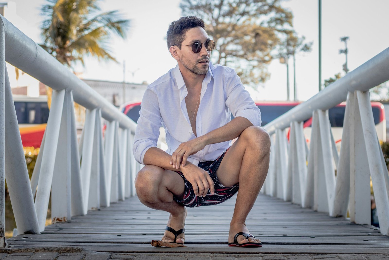 man in white dress shirt sitting on wooden bridge during daytime