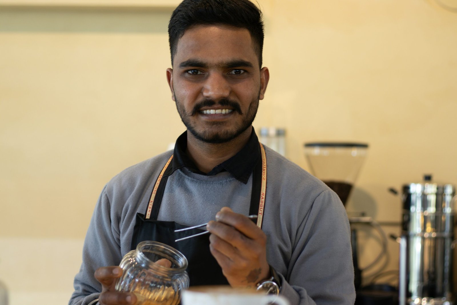 A man in an apron holding a glass jar