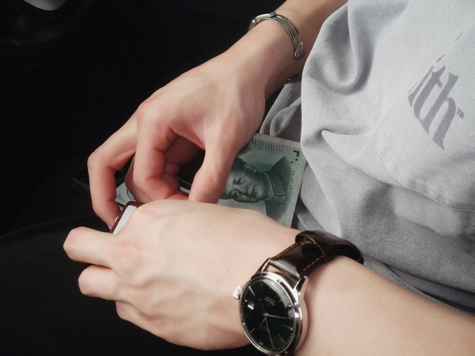 A person holding a watch and a money in their hand