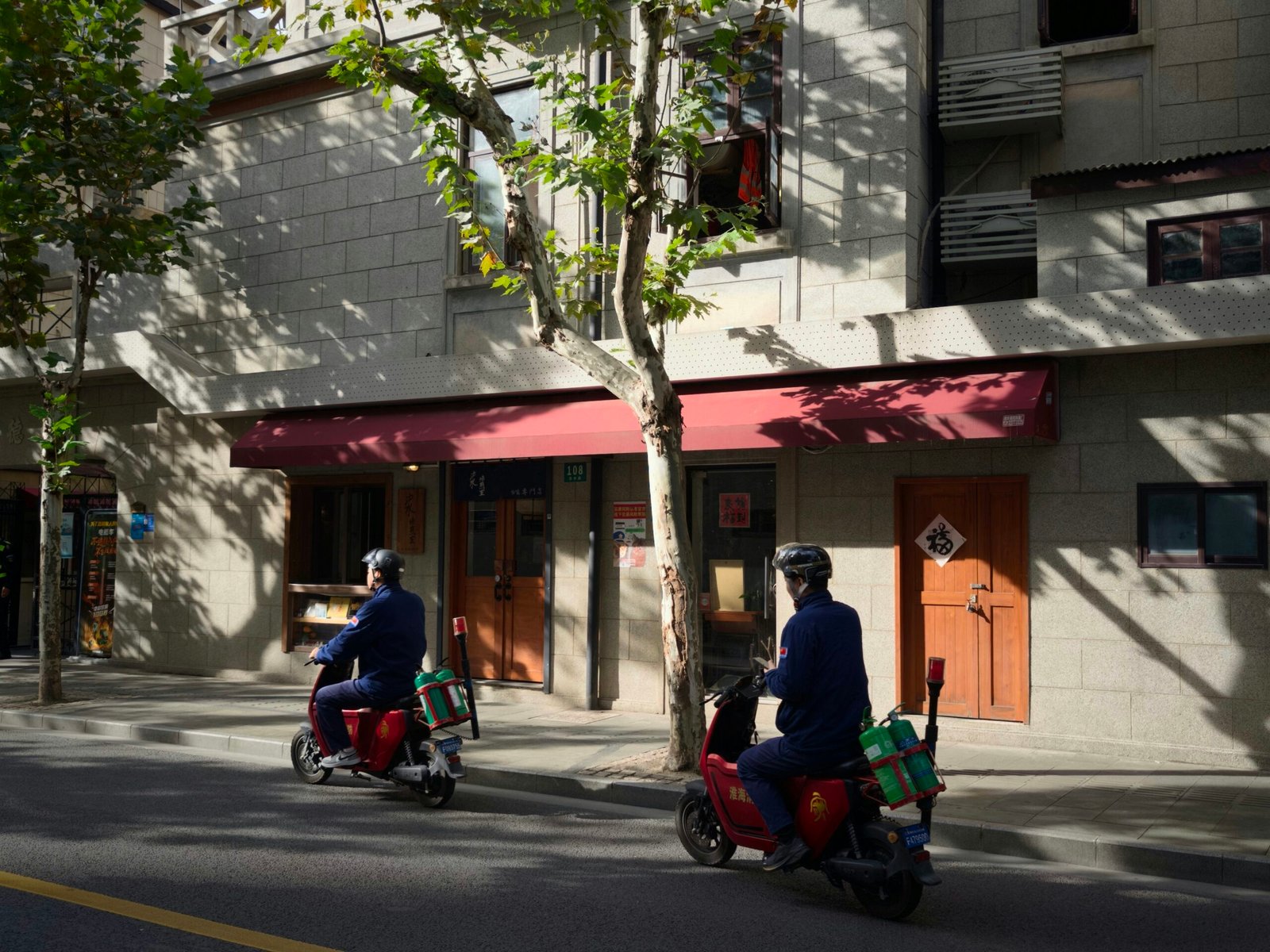 Two people riding electric scooters on a street.