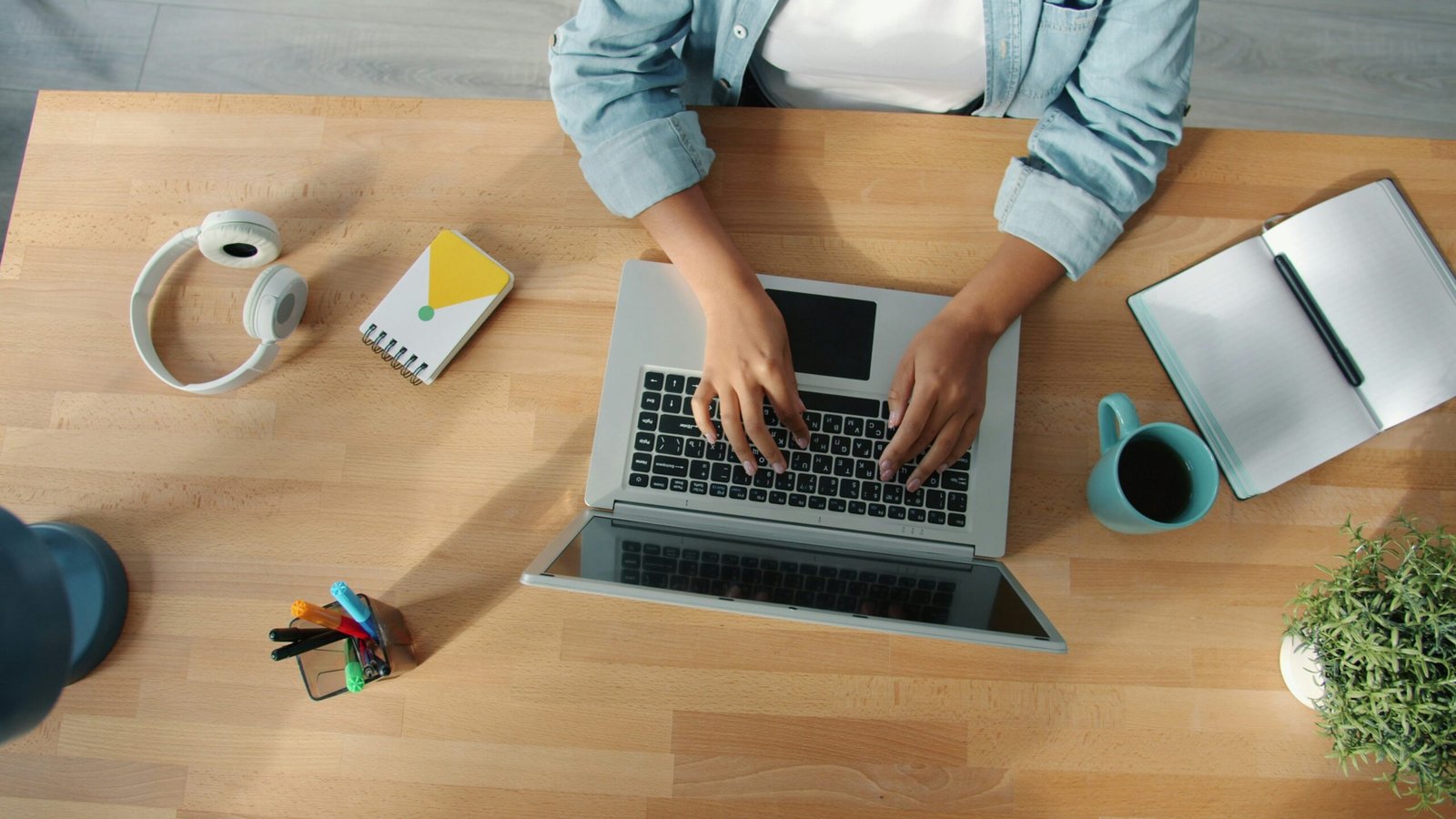 Person typing on a laptop at a wooden desk.