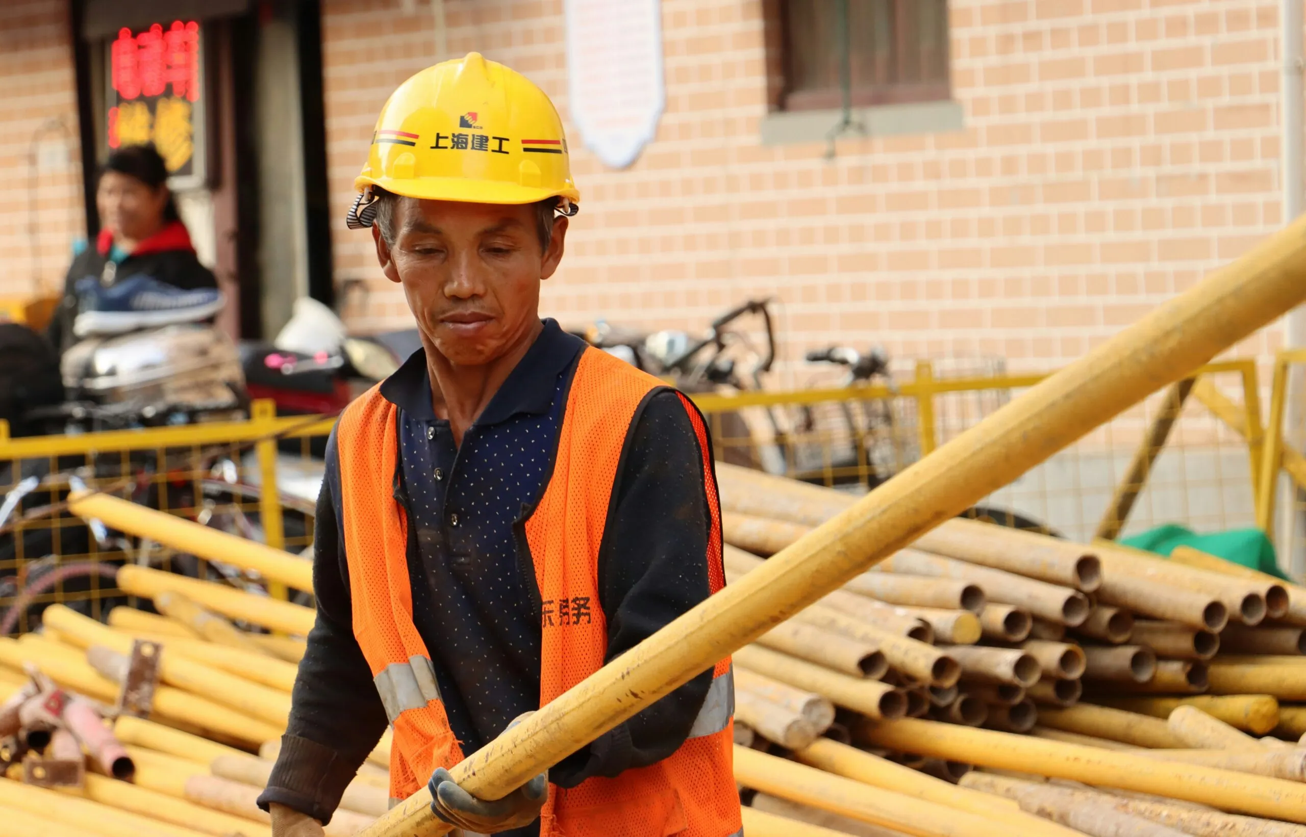 a man wearing a hard hat and carrying a large wooden stick