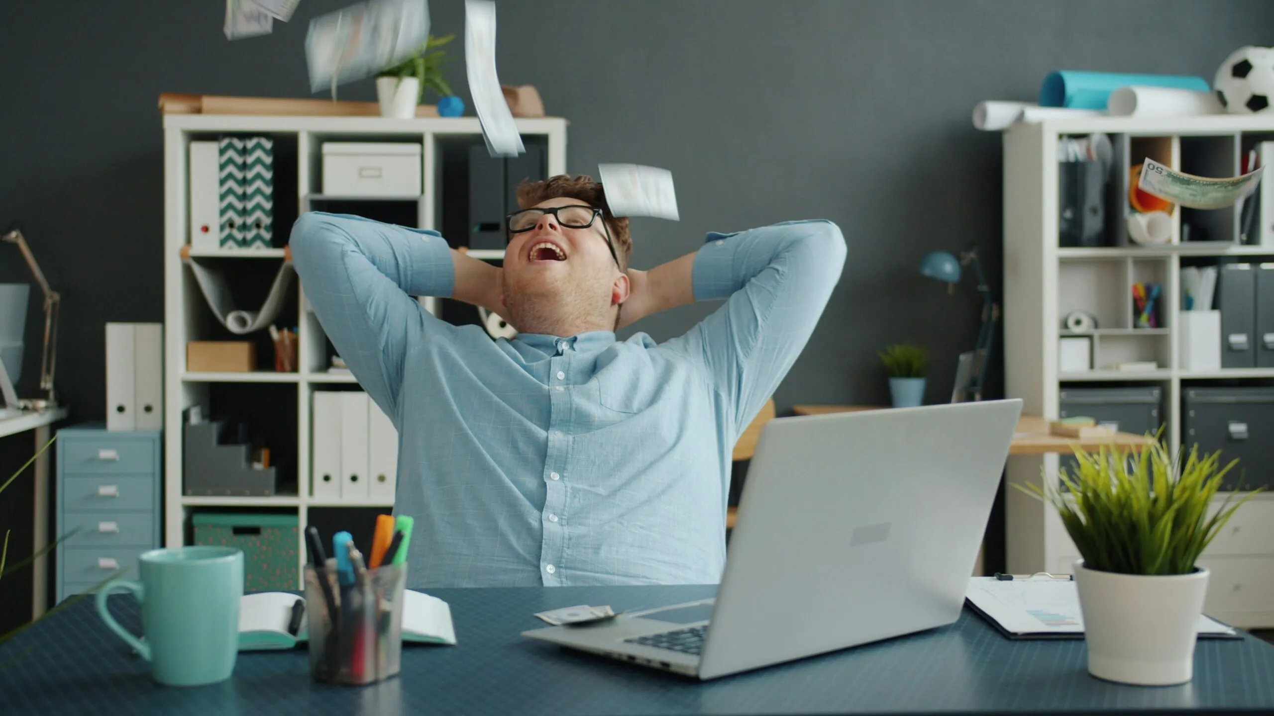 Man celebrating success by throwing papers in office
