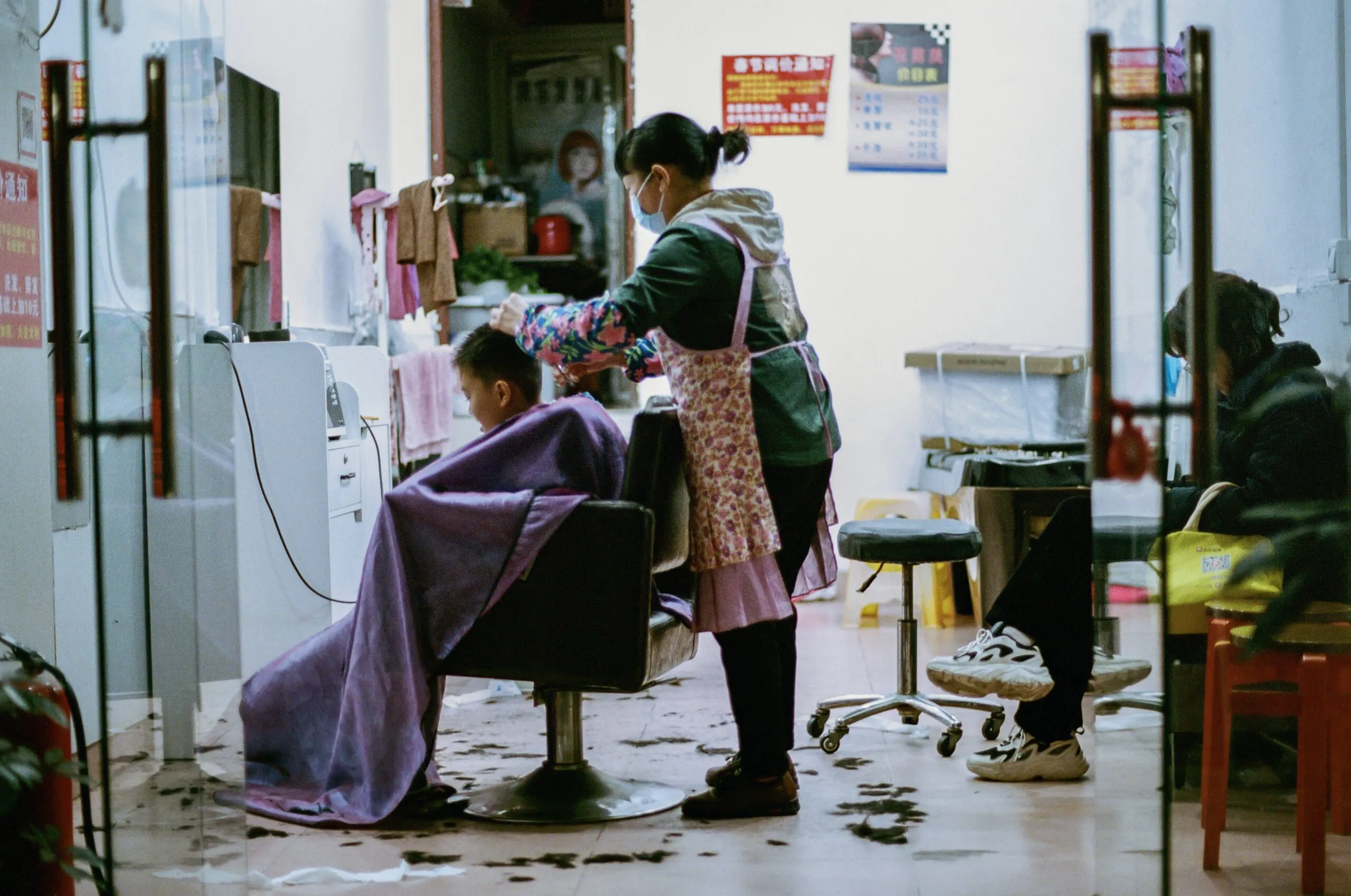 A hairstylist cuts a child's hair in a salon.