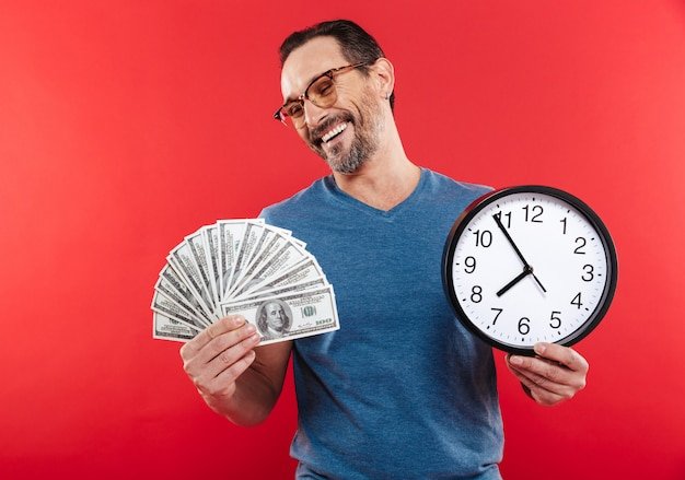Adult cheerful positive man holding money and clock.