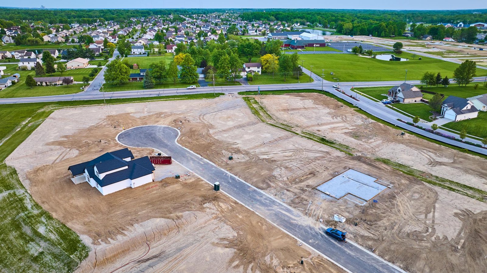 Aerial housing construction site new neighborhood cement slab one completed house distant houses