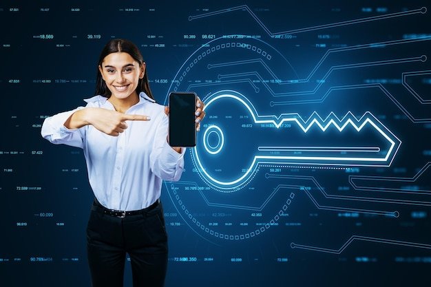 Attractive young european businesswoman pointing at mobile phone with glowing key hologram on blurry background Virtual house and future concept