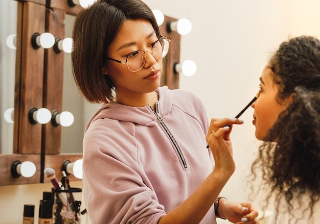 Beautician applying make-up on woman in beauty spa