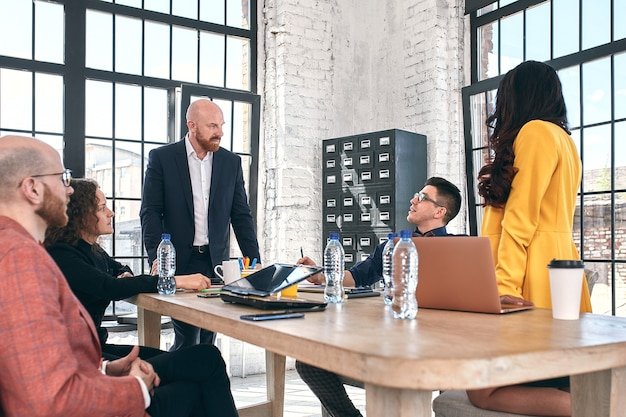 Beautiful business people are using gadgets, talking and smiling during the conference in office