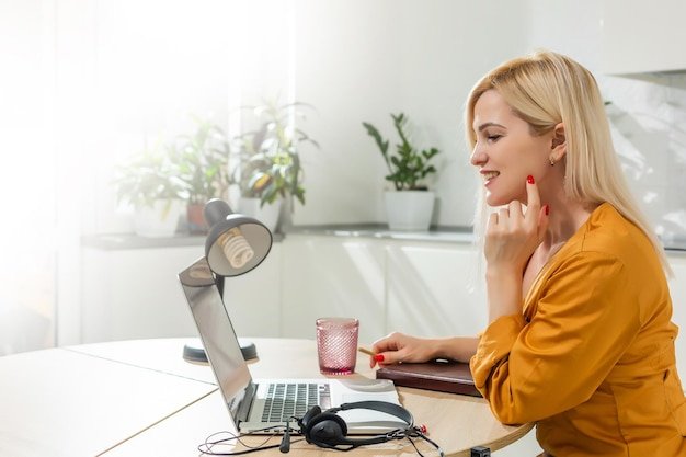 Beautiful caucasian woman working on laptop. Kitchen background.