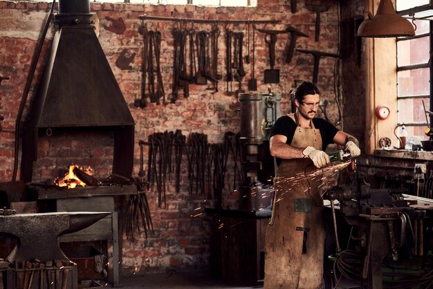 Blacksmith metal worker or man in factory and sparks manual labor for safety on hot steel with flash or welder Workshop welding and iron tools for manufacturing craft trade and plant grinder