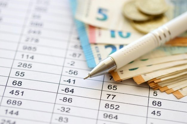Business concept with many euro money bills and pen on schedules with calculations