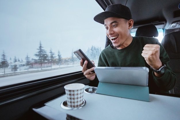 Busy young man working while going out by a van male business using mobile phone and tablet while tr