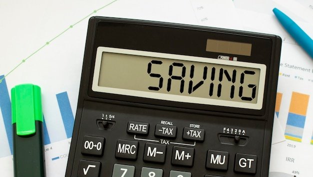 A calculator labeled SAVING lies on financial documents in the office.