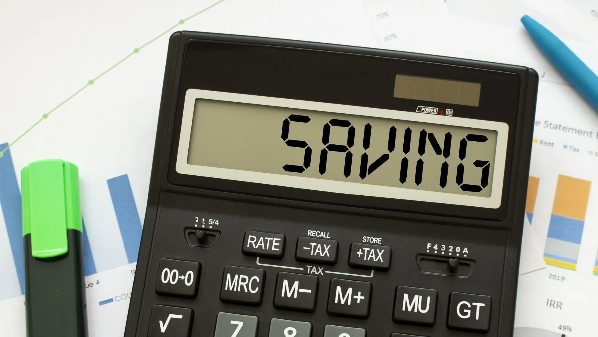 A calculator labeled SAVING lies on financial documents in the office.
