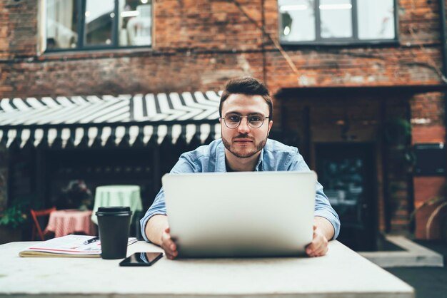 Calm male browsing laptop in street