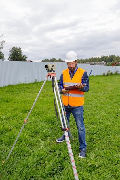 A civil engineer writes down the readings of the optical level on a piece of paper in a folder