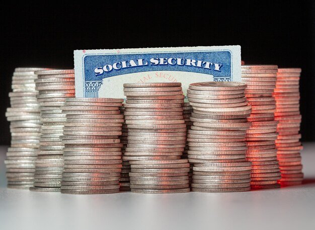 Close-up of coins stacked by social security card on table against black background