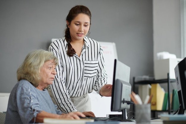 Computer training class teacher working with senior woman