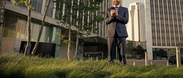 Cropped businessman in suit typing message on phone outside the office communication
