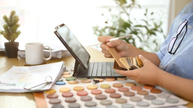 Cropped shot decorator choosing laminate floor samples at desk Home design and renovation