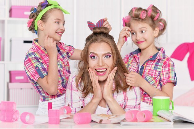 Cute  tweenie girls with mother   in hair curlers  doing hairstyle for their mother