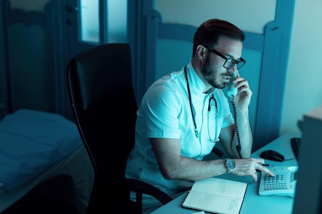 Doctor dialing while using phone in medical examination room at clinic