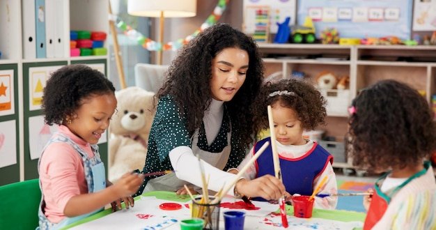 Education kids and students painting with teacher for art creative talent or motor skill development in preschool Learning drawing and teaching happy girls in class for lesson or help with color