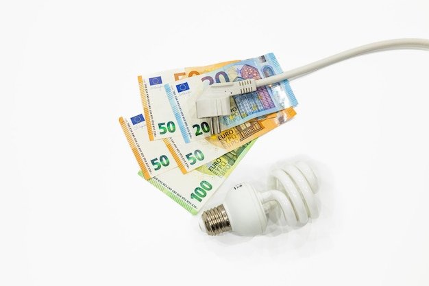 Electric plug light bulb and the euro money banknotes. Concept of expensive electricity costs