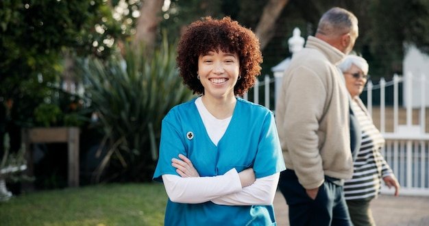 Happy crossed arms and portrait of nurse outdoor for fresh air wellness and relax at nursing home Nature backyard and confident woman with pride for assisted living senior care or caregiver