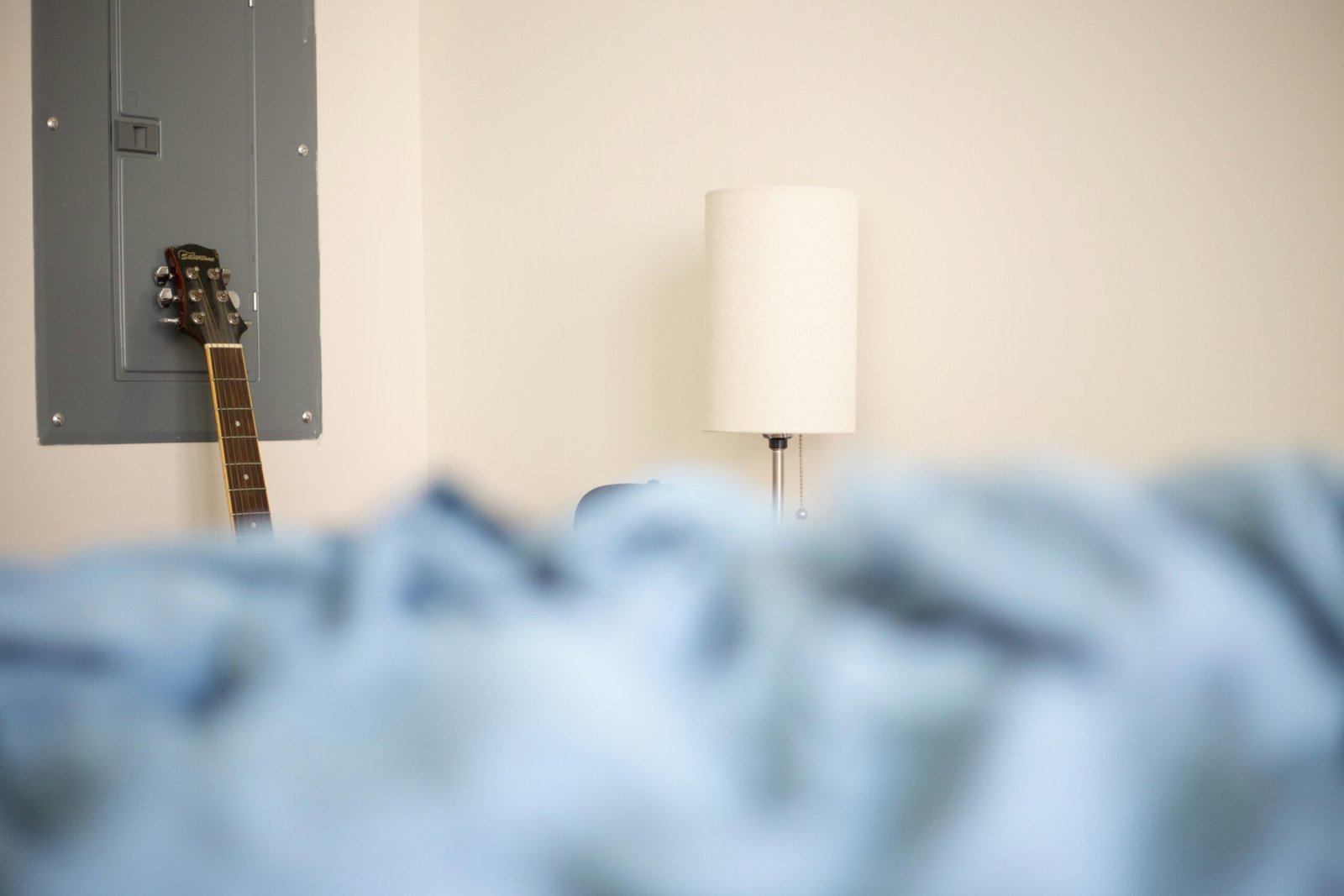 a guitar leaning against a wall next to a lamp