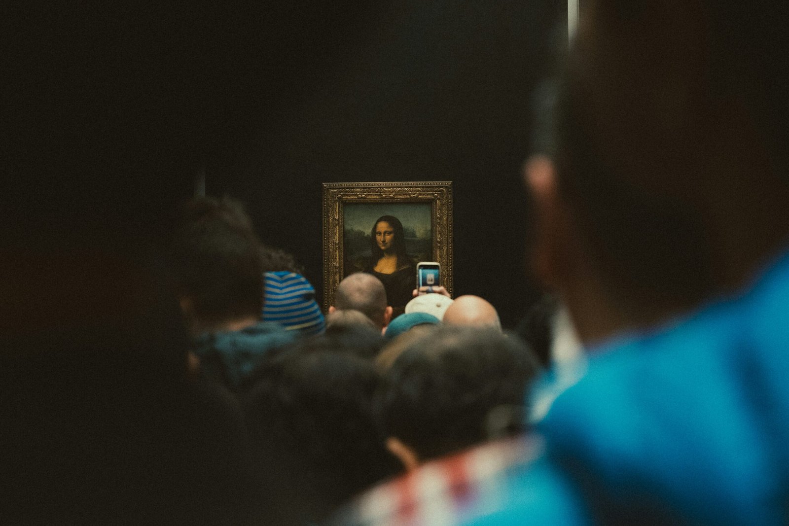 People crowd around the mona lisa painting.