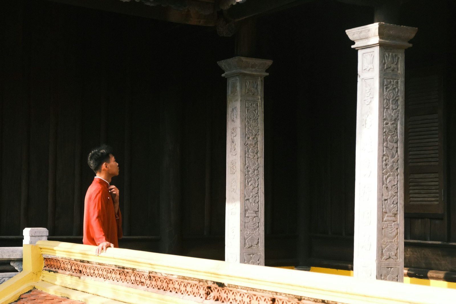 Person in red clothing stands near pillars.