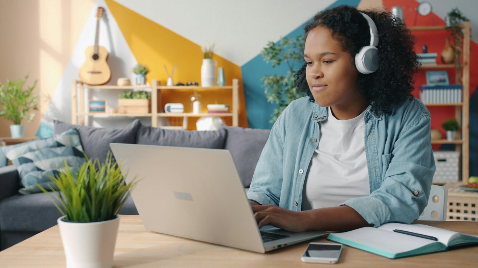 Young woman wearing headphones using laptop at desk.