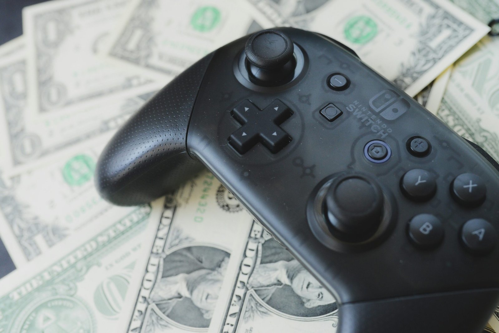 a video game controller sitting on top of a pile of money