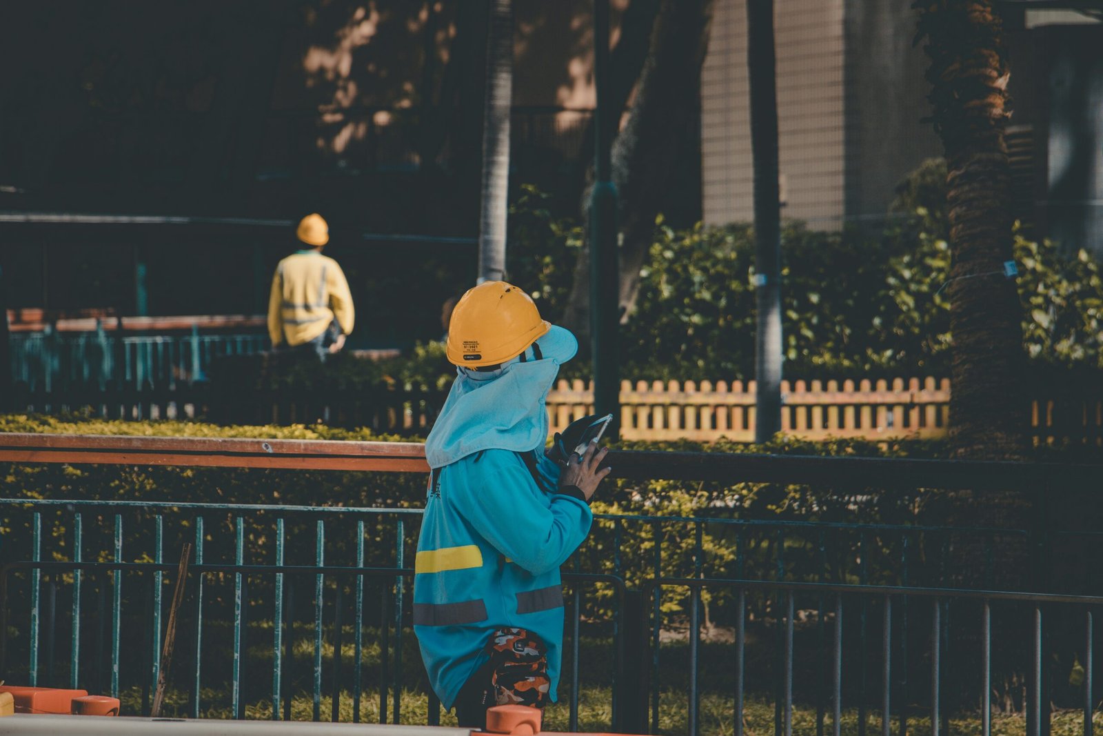 person wearing yellow hard hat near fence