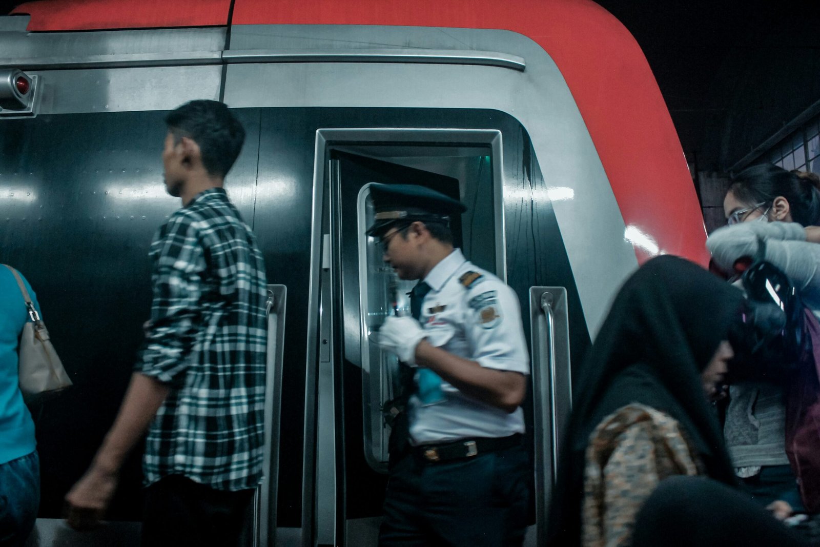 Train conductor and passengers at a station entrance.