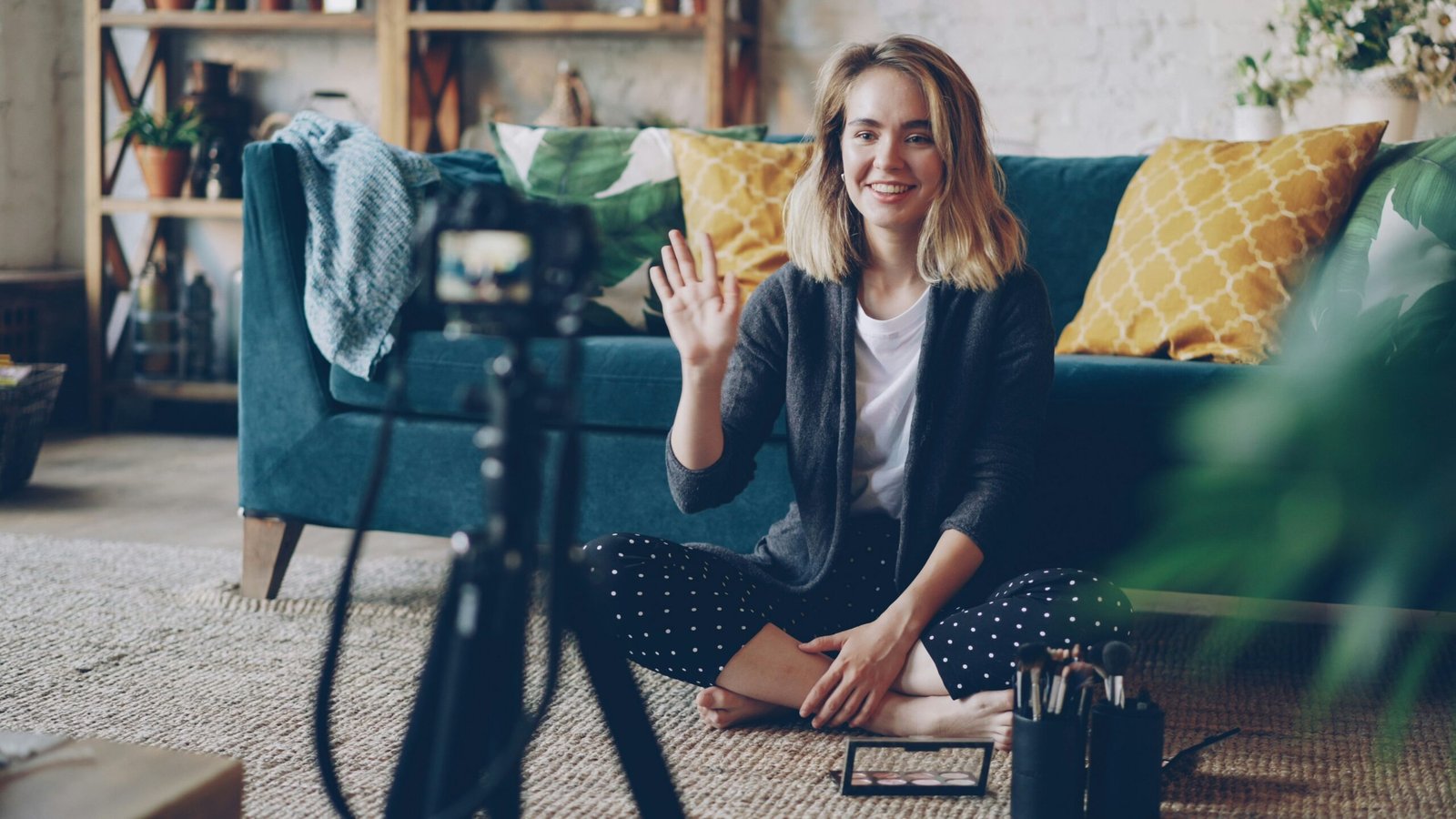Woman waving hello at camera in living room.