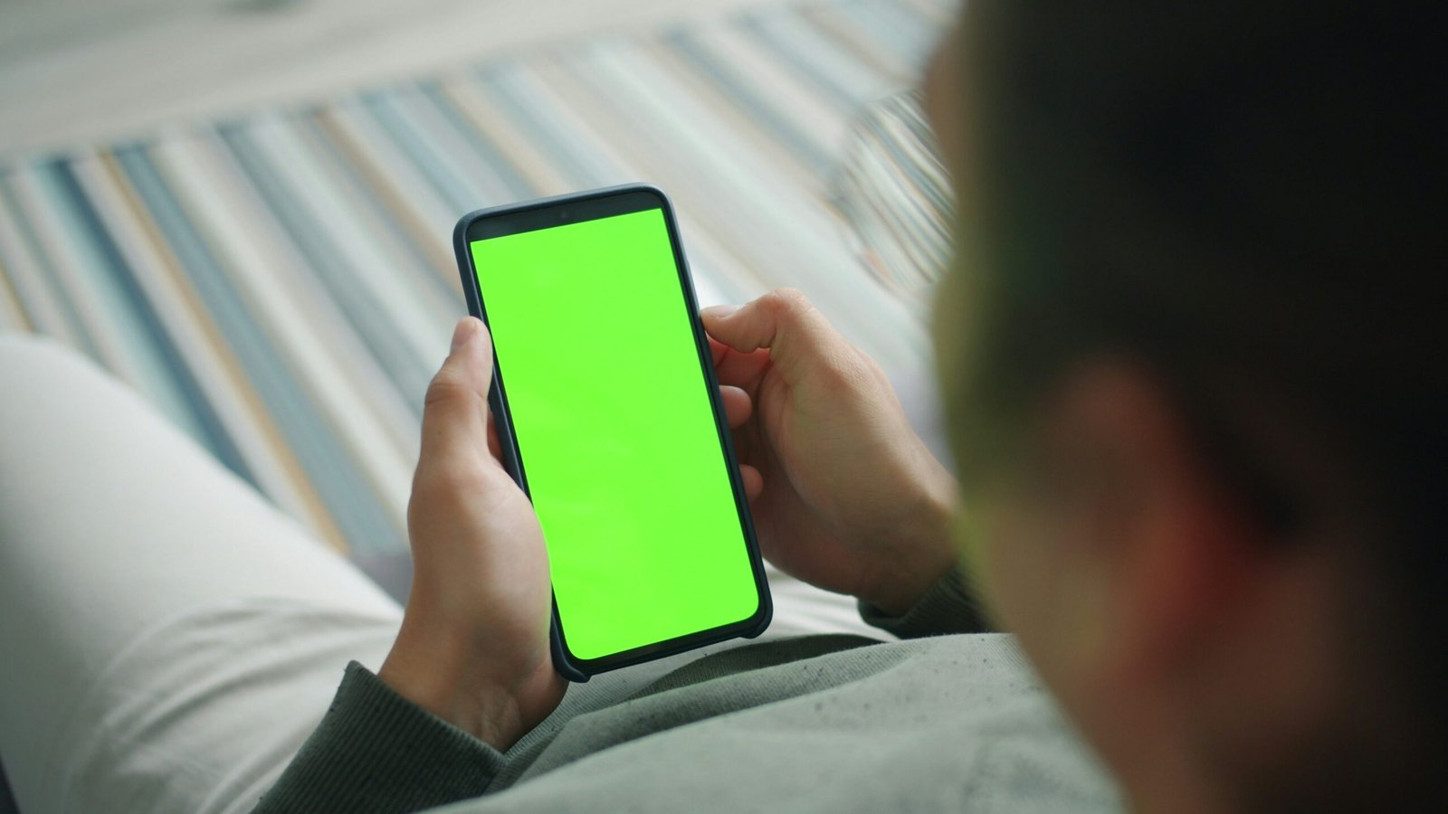 Person holding a smartphone with a green screen.