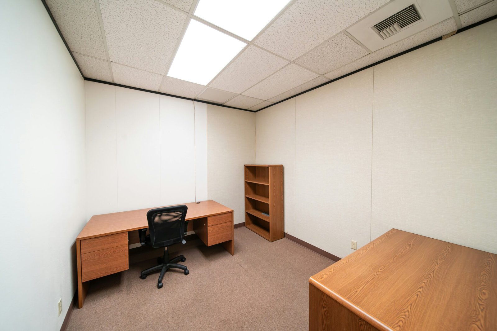 an empty room with a desk and a book shelf
