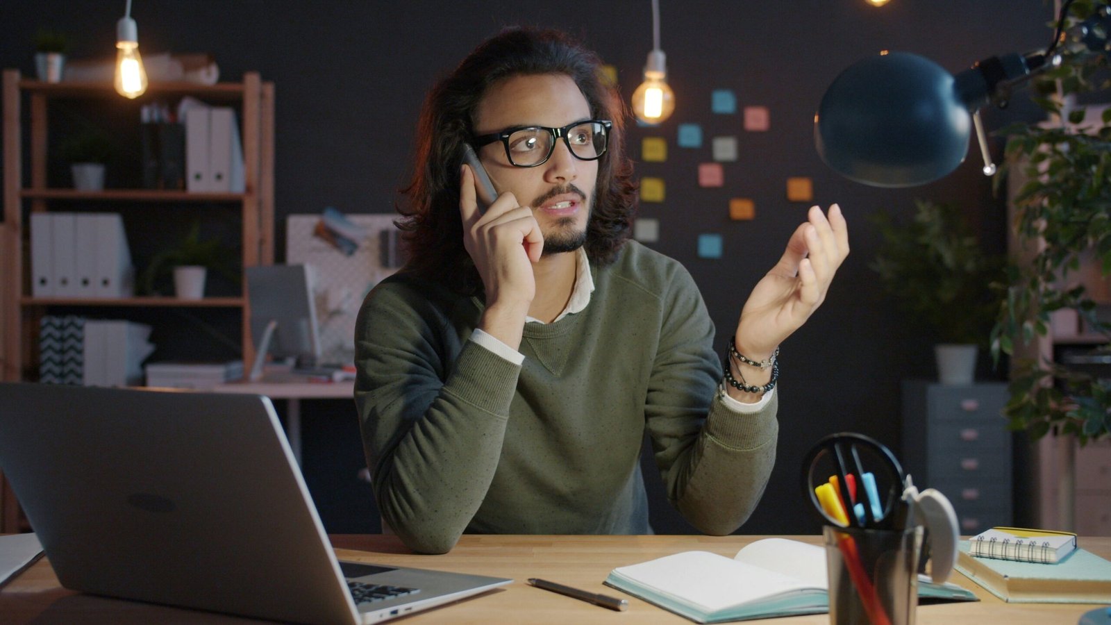 Man talking on phone at desk with laptop.