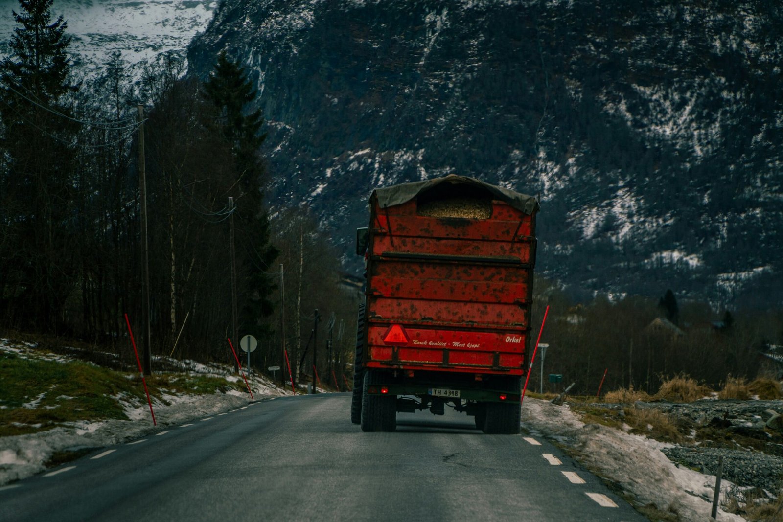 A red truck driving down a snow covered road