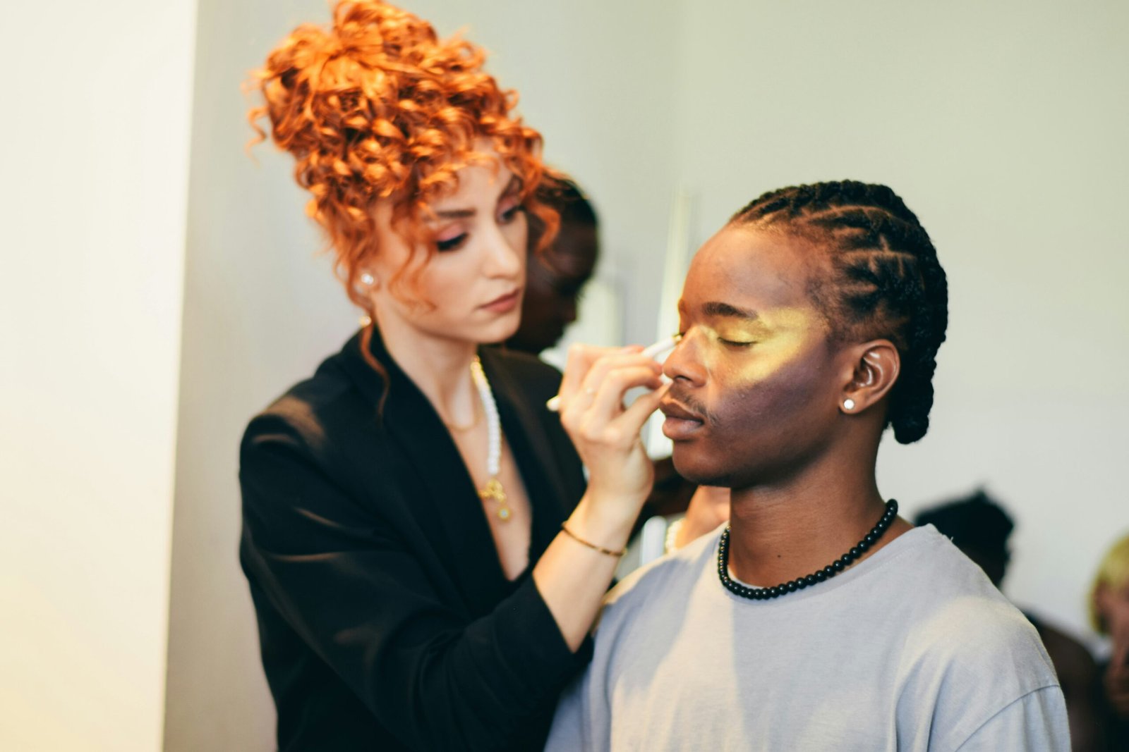 Makeup artist applying gold eyeshadow to a man.