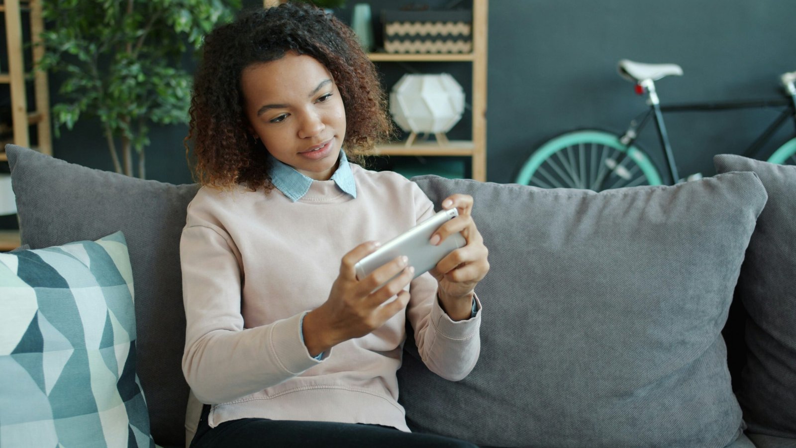 Young woman playing game on smartphone at home