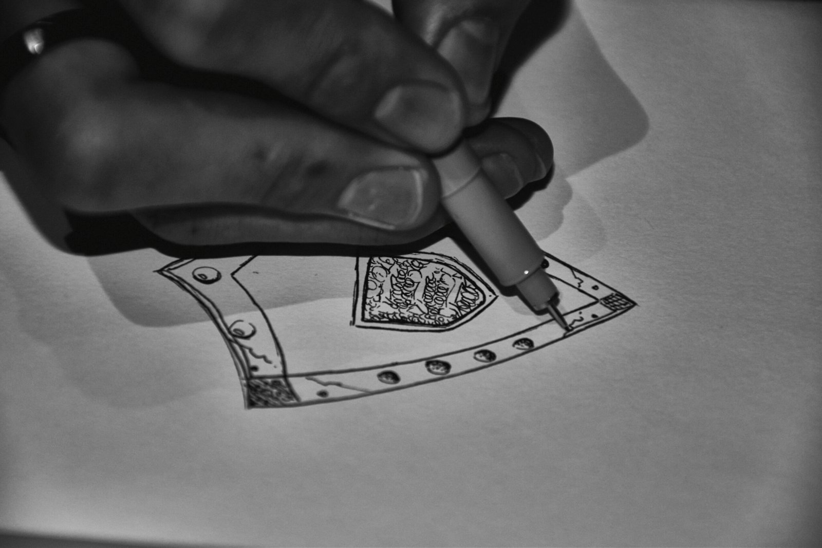 Artist drawing intricate design on paper with pen.