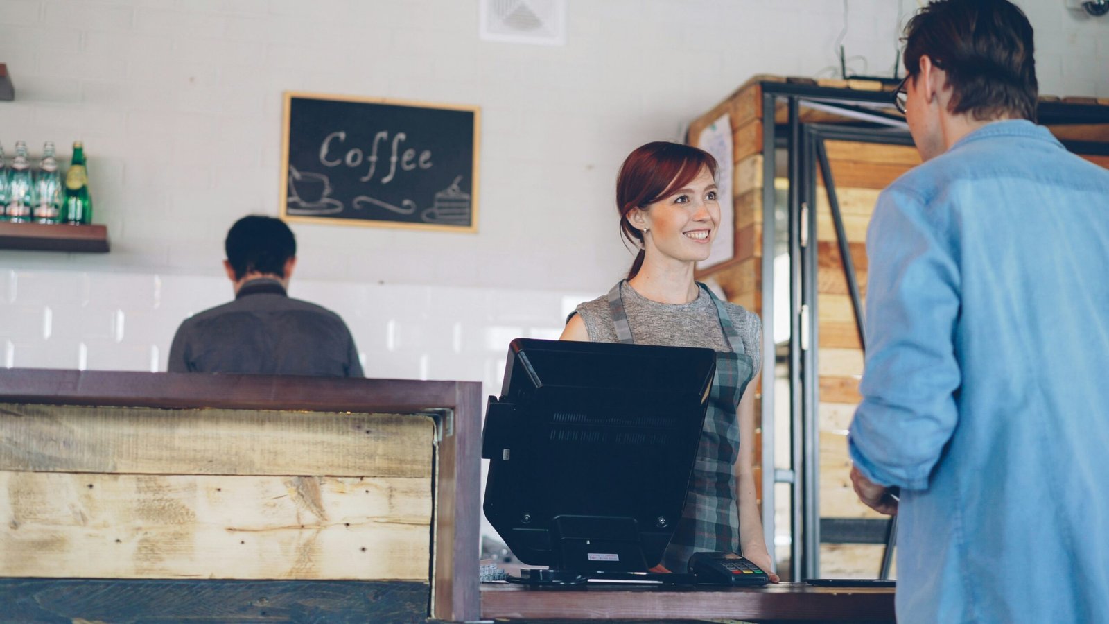 A barista serves a customer in a coffee shop.