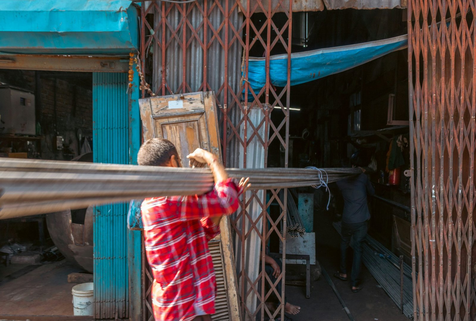 Man carries metal poles through a shop entrance.