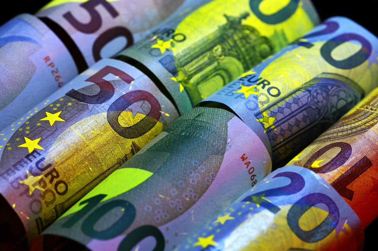 Rolled euro banknotes in various denominations.